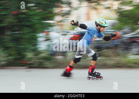 Ukraine, Kyiv - 20 June 2021: Boy training for inline skates. Rollerblade Inline Skates, Author Helmet, Powerslide Protection . Editorial Stock Photo