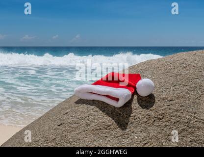 Christmas hat on beach stone and tropical background Stock Photo