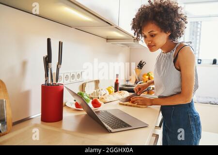 Beautiful lady making a vegetable salad following an online recipe Stock Photo