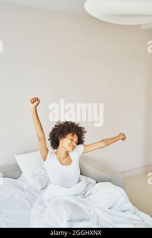 Pleased lady having a stretch after wake-up Stock Photo