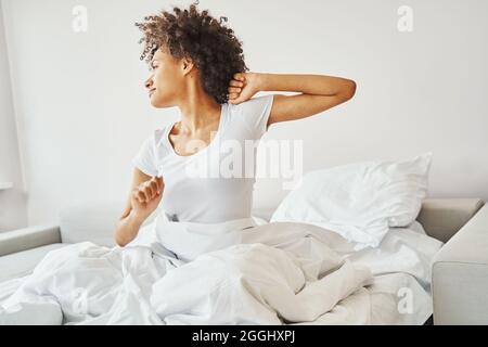 Serene curly-haired lady stretching her arms after sleep Stock Photo