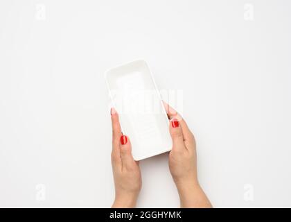 Female hands hold an empty rectangular disposable plastic container on a white background, top view Stock Photo