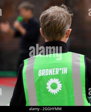 Cottbus, Germany. 01st Sep, 2021. A helper at the election campaign event of Bündnis 90/Die Grünen (Alliance 90/The Greens) on Oberkirchplatz wears a green high-visibility vest with the gender-appropriate inscription 'Ordner*in' (steward) during the event. Credit: Soeren Stache/dpa-Zentralbild/dpa/Alamy Live News
