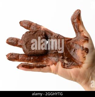 female hand holding a melted piece of dark chocolate, hand smeared with chocolate on a white background Stock Photo