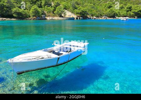 Old wooden boat on surface of clear blue sea Stock Photo
