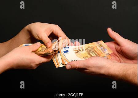 People count money, counting euro bills by man and woman, money on black background. new Stock Photo