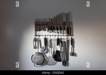 Group of Kitchen Utensils Hanging Indoors in Evening Light Stock Photo