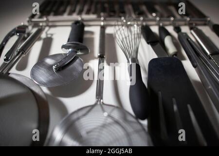 Group of Organized Kitchen Tools Hanging on Home Kitchen Wall Stock Photo