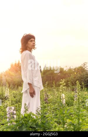 One Mexican woman wearing all white at flower field during sunset Stock Photo