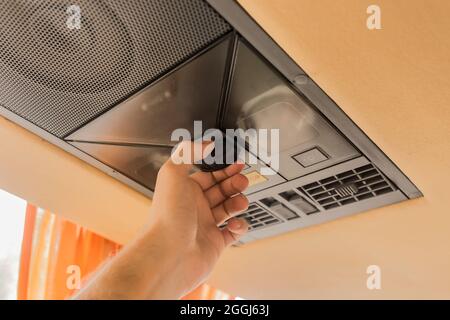 A man's hand touches the jsb in the cooling system in the ceiling of a tourist bus. Stock Photo