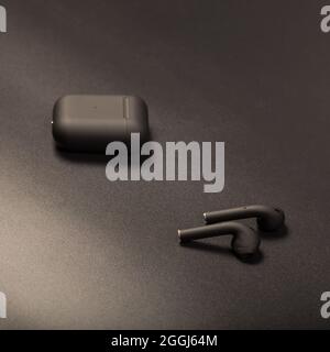Black wireless earbids with charging case, close up on black background. Stock Photo