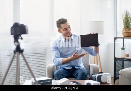 Arab male vlogger making video review of innovative tablet pc, using camera at home, mockup on touch pad screen Stock Photo