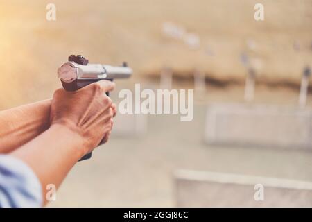 Gun in the hands of a girl, close-up arms. Stock Photo