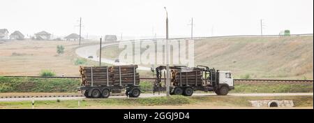 The machine transports wooden logs. Cargo transportation of wood and boards. Stock Photo