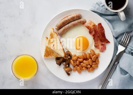 Typical classic english breakfast. Delicious eggs, bacon, mushrooms, beans and sausages on plate Stock Photo