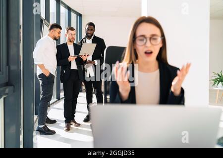 Frustrated female office worker looking at laptop Stock Photo