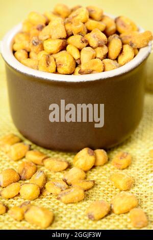 roasted and salted corn in ceramic pot over yellow jute Stock Photo
