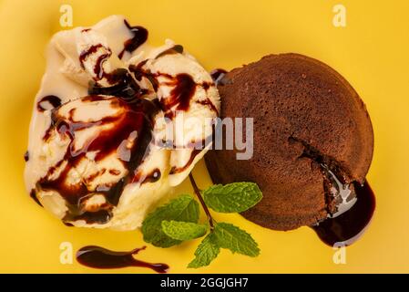 petit gateau with vanilla ice cream and a sprig of mint on yellow plate Stock Photo