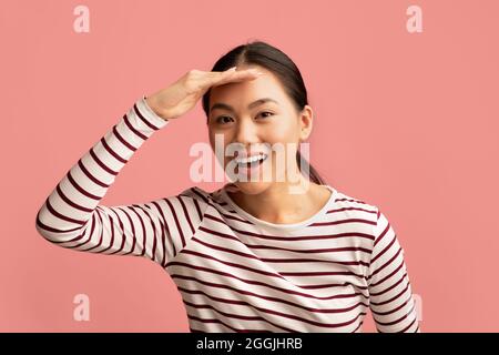 Asian Woman Keeping Hand Near Forehead And Looking At Camera With Interest Stock Photo