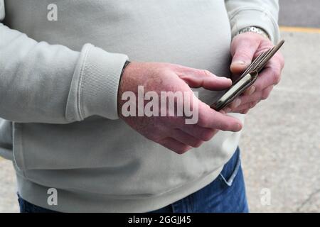 Man searching on touch screen phone in a brown leather case Stock Photo