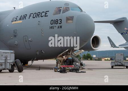 U.S. Air Force Airmen assigned to the 721st Aircraft Maintenance Squadron slide a new nose landing gear wheel and tire assembly onto the axle of a C-17 Globemaster III aircraft during Operation Allies Refuge at Ramstein Air Base, Germany, Aug. 30, 2021. When one tire is worn down, the Airmen must replace both tires. (U.S. Air Force photo by Tech. Sgt. Anthony Plyler) Stock Photo