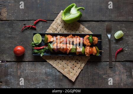 Chicken kebabs or doners grilled with saute vegetables on a black tray. Top view. Stock Photo
