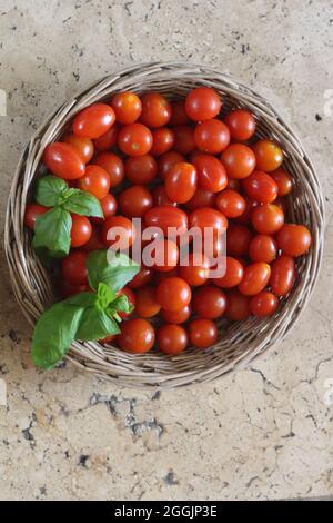 Tomatoes and basil on stone surface Stock Photo