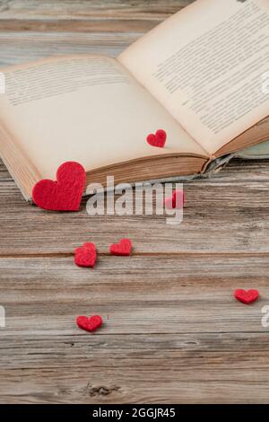 valentines day concept with an old book opened on a wooden table decorated with red hearts Stock Photo