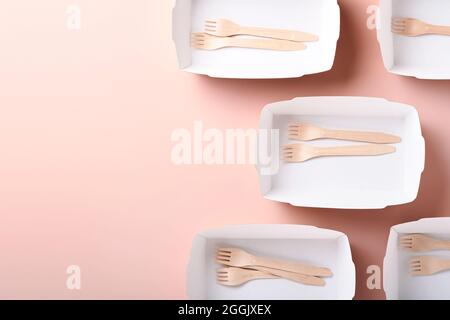 Paper cups, dishes, bag, wooden forks, drinking straws, fast food containers, wooden cutlery on pink background. Eco craft paper tableware. Recycling Stock Photo