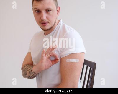 Protective health, vaccinating of population and prevention against flu and covid-19 pandemic. caucasian man show shoulder with band aid after injecti Stock Photo