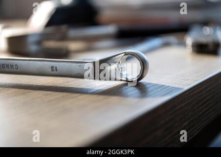A portrait of a metal box end wrench lying on a wooden table. The tool is used in construction or to repair something. Stock Photo