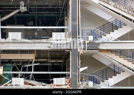 The open part of the destroyed facade of a concrete house with visible communications and flights of stairs. Stock Photo