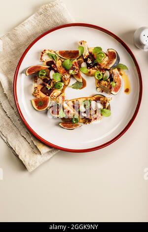 Gourmet salad with ripe figs, goat chevre cheese, fresh cucumber roll, beetroot and mustard leaves with tomato sauce. Summer salad without meat. Delic Stock Photo
