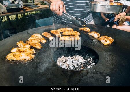 Frying herbed fish filets on a plancha barbeque grill Stock Photo