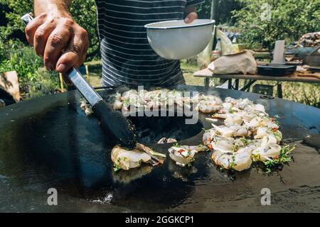 Frying herbed king prawns on a plancha barbeque grill with thyme Stock Photo