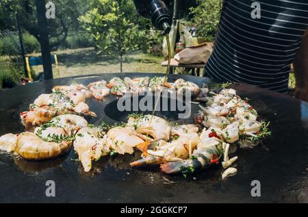 Frying herbed king prawns on a plancha barbeque grill with thyme Stock Photo