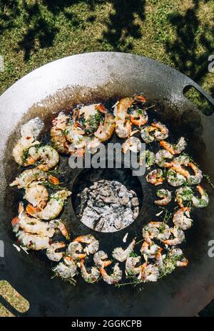 Frying herbed king prawns on a plancha barbeque grill with thyme Stock Photo