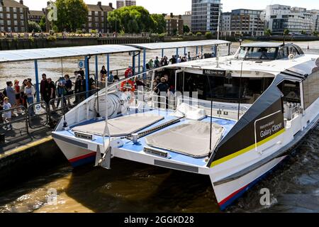 London, England - August 2021: People getting off a Thames Clipper water taxi on the River Thames at Greenwich pier. Stock Photo