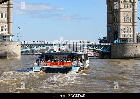 London, England - August 2021: Thames Clipper water taxi on the River Thames approaching Tower Bridge. Stock Photo