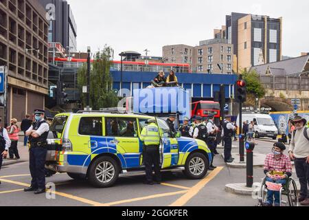 London, United Kingdom. 30th August 2021. Police guard a van to which protesters shackled themselves in Tower Hill. Extinction Rebellion protesters marched from News UK to Tower Bridge as part of their two-week Impossible Rebellion campaign.
