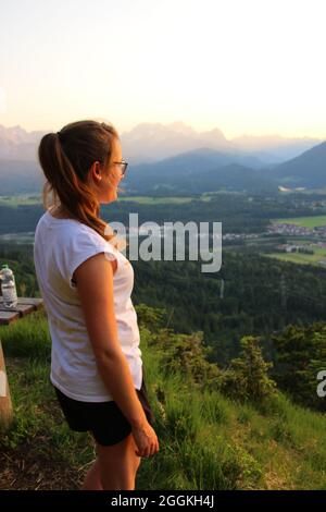Young woman enjoys the view during an evening mountain hike, view of Krün, Wetterstein Mountains, Isar Valley, Upper Bavaria, Bavaria, Germany, Europe Stock Photo