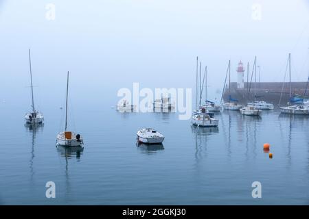 Foggy mood in the harbor of Erquy, in the background the small lighthouse on the pier, France, Brittany, Département Côtes d´Armor, Côte de Penthièvre Stock Photo