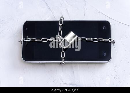 Close-up of a smartphone locked with a chain lock. Data privacy concept. Stock Photo