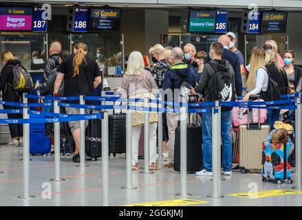 Duesseldorf, North Rhine-Westphalia, Germany - Duesseldorf Airport, holiday start in NRW, vacationers stand in line with suitcases at the Condor check-in counter in times of the corona pandemic on their way to summer vacation, vacationers should have a PCR test, ID / QR code keep ready. Stock Photo