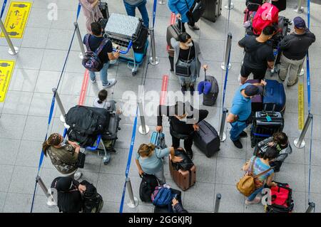 Duesseldorf, North Rhine-Westphalia, Germany - Duesseldorf Airport, holiday start in NRW, vacationers stand with suitcases in a queue at the check-in counter in times of the corona pandemic on their way to summer vacation. Stock Photo