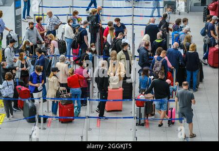 Duesseldorf, North Rhine-Westphalia, Germany - Duesseldorf Airport, holiday start in NRW, vacationers stand with suitcases in a queue at the check-in counter in times of the corona pandemic on their way to summer vacation. Stock Photo