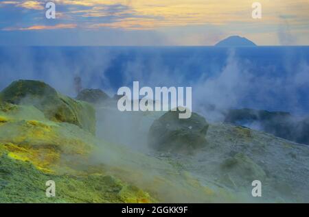 Hikers walking through fumaroles smoke on Gran Cratere rim, Vulcano Island, Aeolian Islands, Sicily, Italy Stock Photo