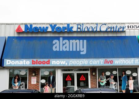 Massapequa, New York, USA - 4 August 2021: The entrance to a New York Blood Donation center with a blue awning with the text donate blood now people c Stock Photo