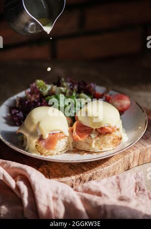 Eggs Benedict with smoked salmon, Hollandise sauce and green salad Stock Photo