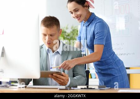 Smiling business colleagues sitting at table working at laptop discussing project or idea together. Stock Photo